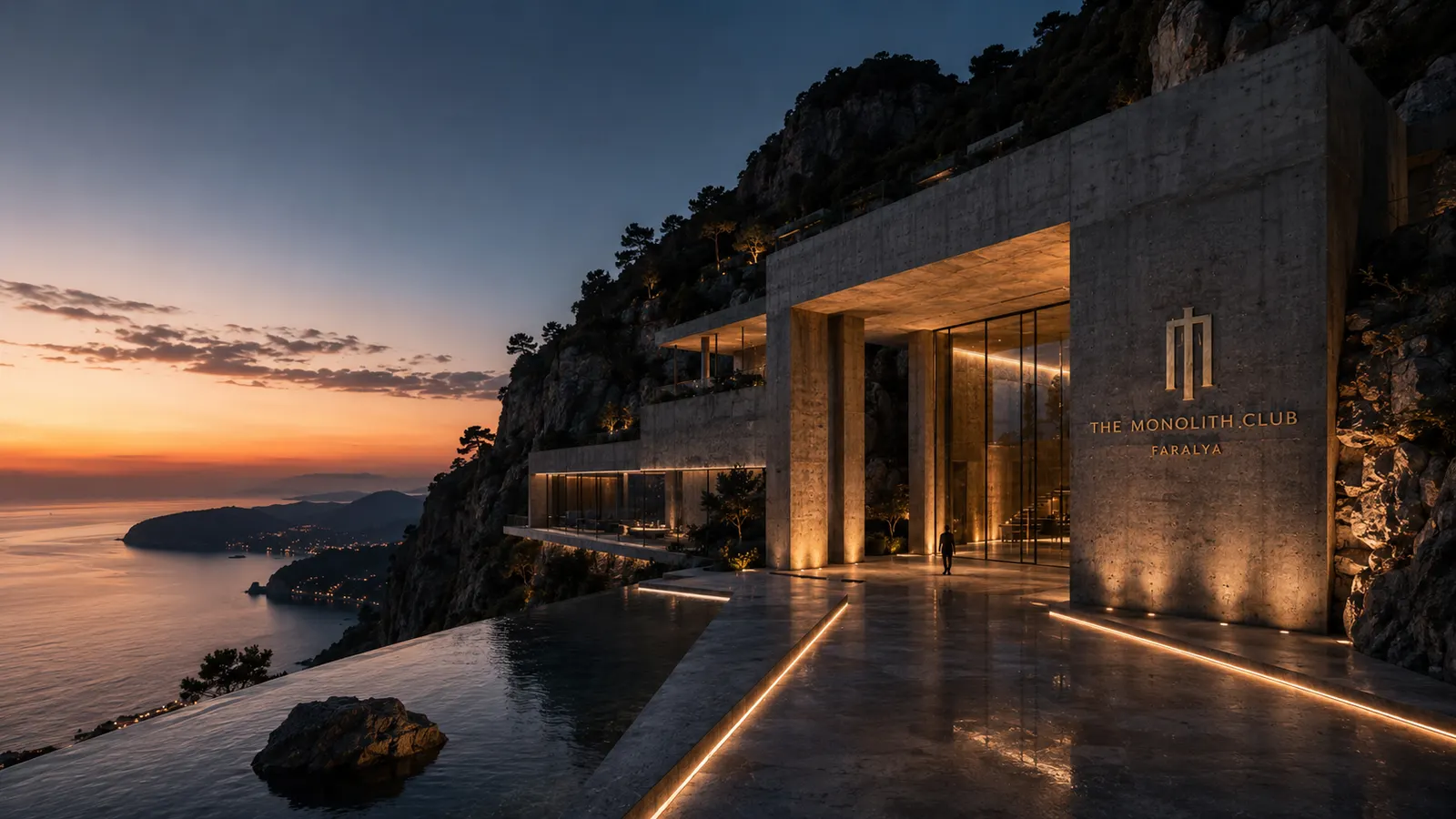 The estate drawn into the cliff at last light, its long glazed face open above an infinity pool, sea and sunset beyond.